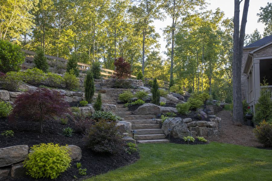 Tiered stone retaining walls and steps on a landscaped slope